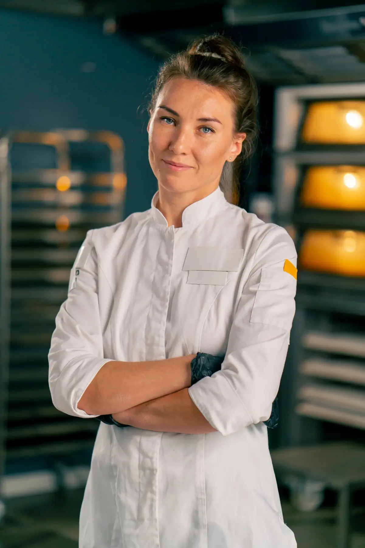 Portrait of Dominika Zawadzka, founder of SliceSync, standing in a professional kitchen with her arms crossed.