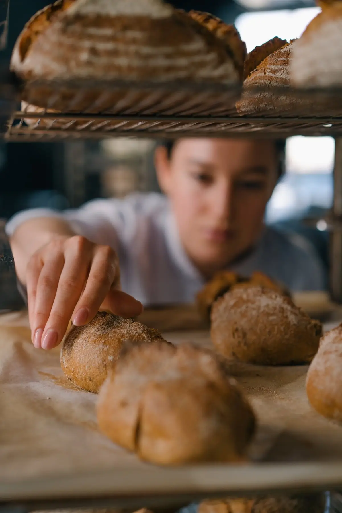 Professional kitchen photo of Dominika Zawadzka, founder of SliceSync, arranging artisan bread in a commercial baking environment. The image highlights her precise, detail-focused approach to food preparation, reflecting SliceSync’s balance of technique, structure, and creativity.