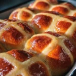 soft hot cross buns with glossy tops and classic crosses in a baking pan