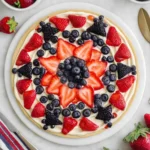 4th of July Fruit Pizza topped with strawberries, blueberries, and cream cheese frosting