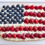American Flag Fruit Pizza decorated with blueberries, strawberries, and creamy frosting in a flag design