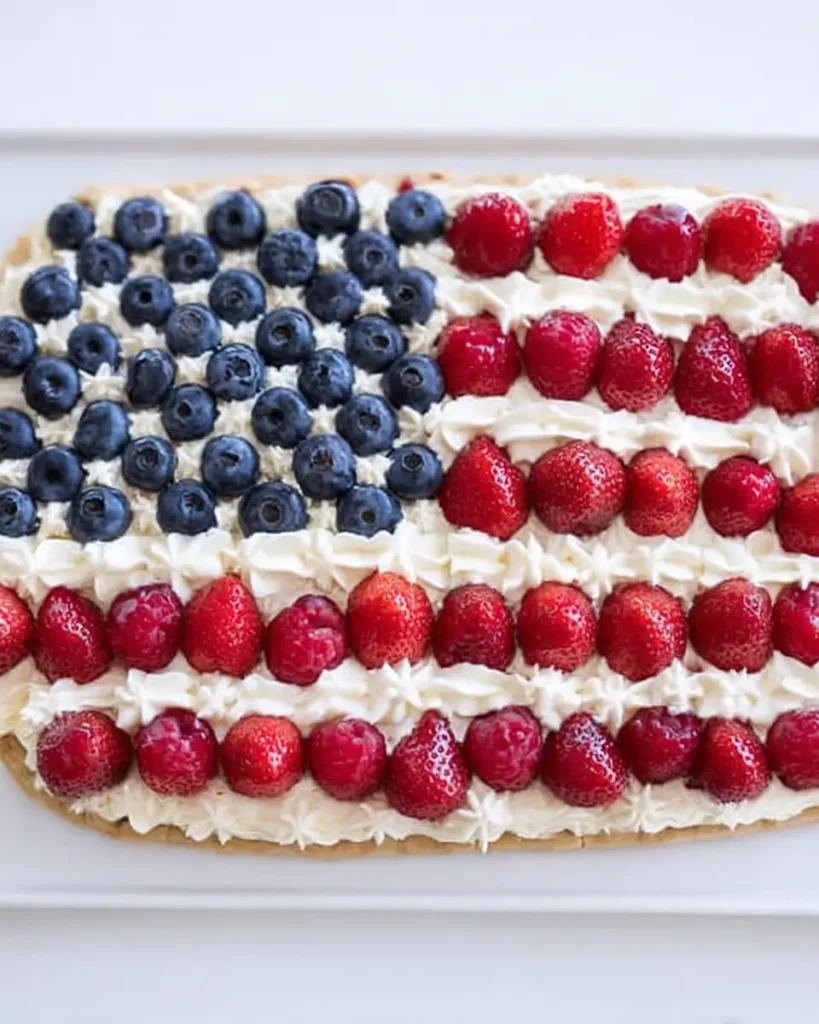 American Flag Fruit Pizza decorated with blueberries, strawberries, and creamy frosting in a flag design