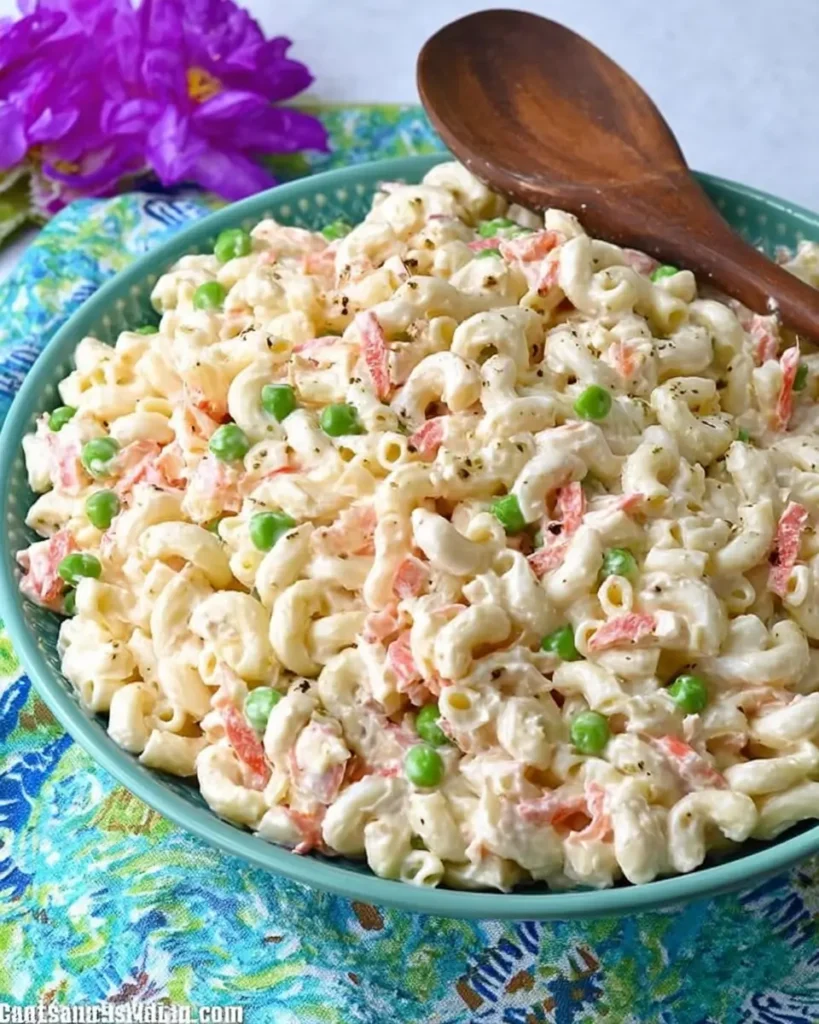 Authentic Hawaiian Macaroni Salad with peas, carrots, and creamy dressing in a serving bowl