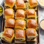 Big Mac-Style Cheeseburger Sliders with sesame buns, melted cheese, and burger sauce on a baking tray