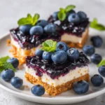 Blueberry Cheesecake Bars with graham crust, creamy filling, and blueberry topping on a plate