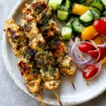 Easy Herby Lemon Skewers served with cucumber salad, cherry tomatoes, and red onions