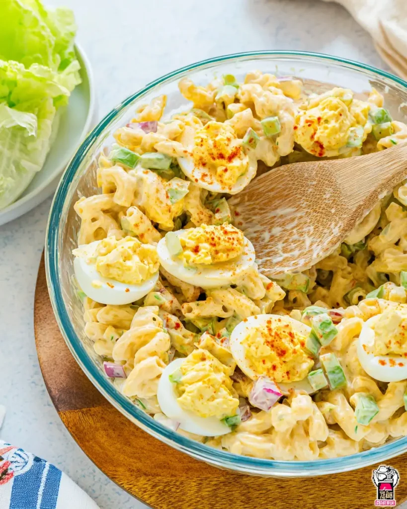 Macaroni Salad with Deviled Eggs in a glass bowl with creamy dressing and paprika topping