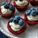 Red White and Blue Cookie Cups topped with cream cheese frosting and fresh blueberries