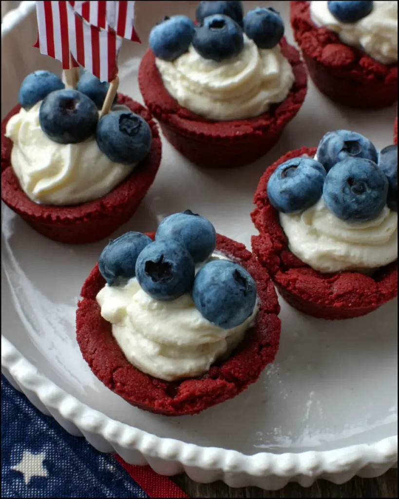Red White and Blue Cookie Cups topped with cream cheese frosting and fresh blueberries