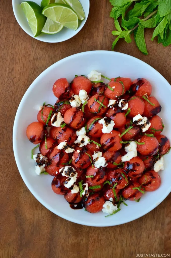 Watermelon salad drizzled with balsamic syrup served on a plate.